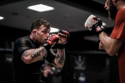 Wear a black round collar T-shirt and a brown boxing gloves
